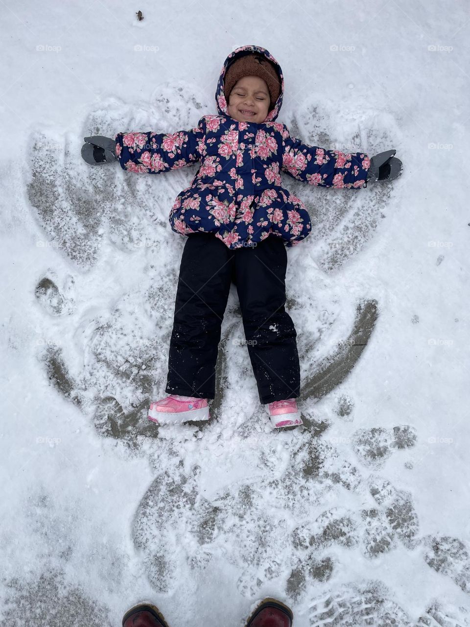 Toddler girl makes snow angel, making snow angels with toddlers, wintertime activities, fun in the snow, making snow angels 