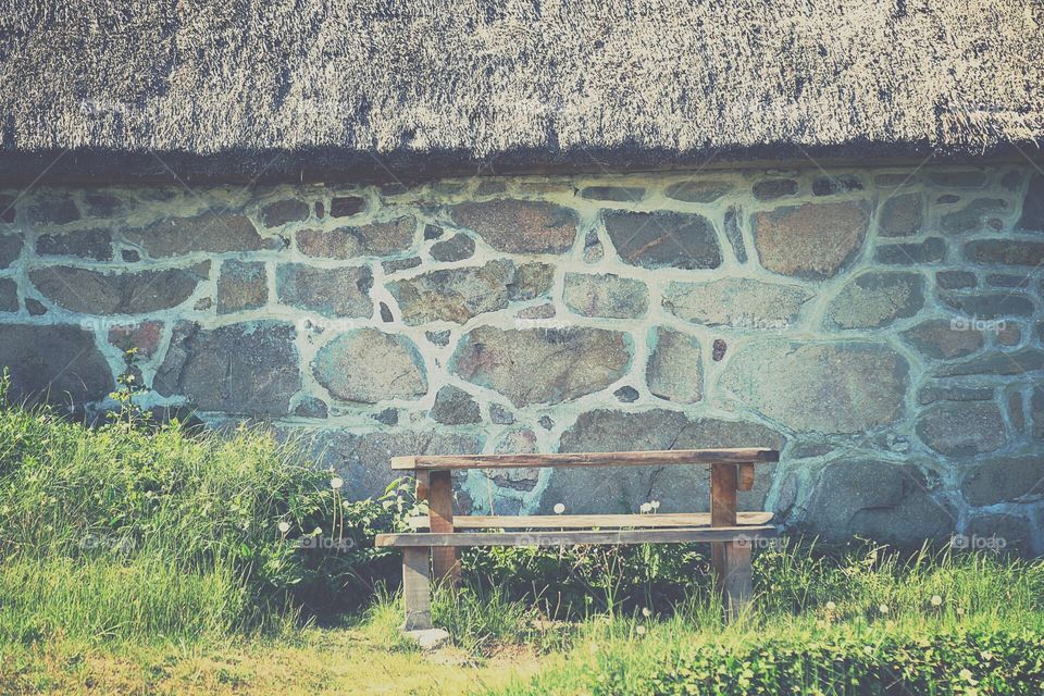 Old stone barn with a wooden bench infront Of it