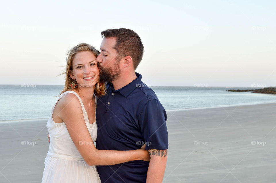 Young couple at the beach and man is kissing woman on the cheek