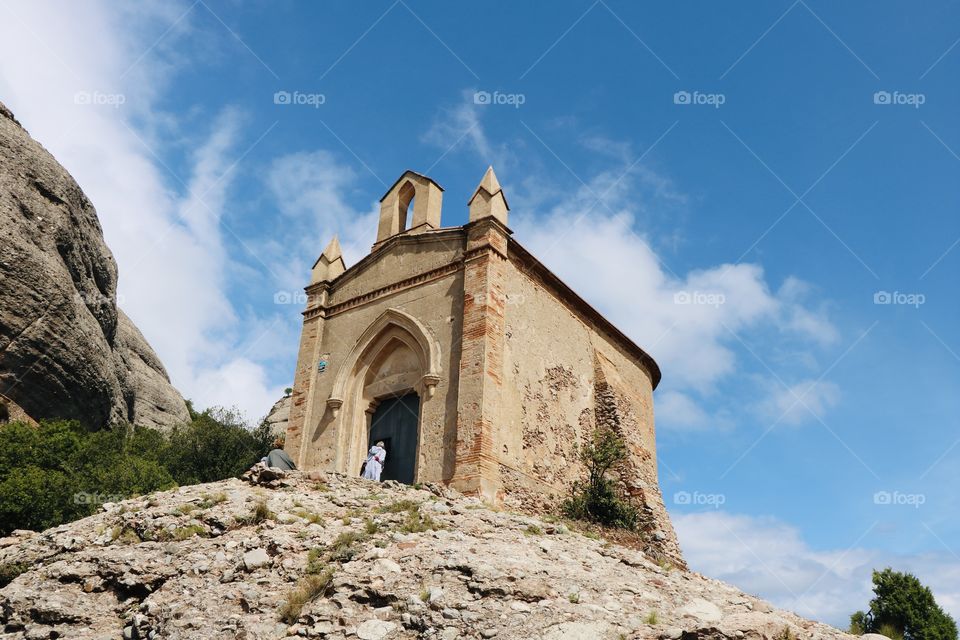 Woman on the door of an old church on top of the rocky hill. Montserrat. Spain 