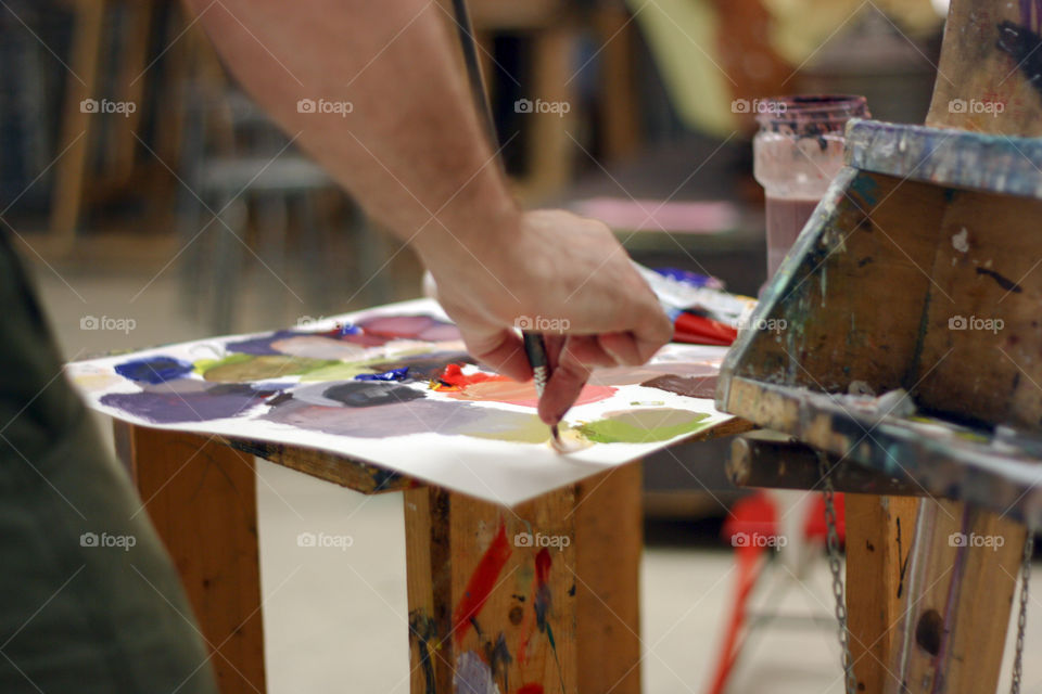 An artist paints and mixes colours in the studio