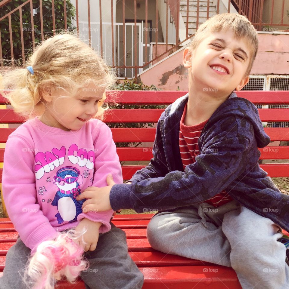 Boy and girl sitting on red bench