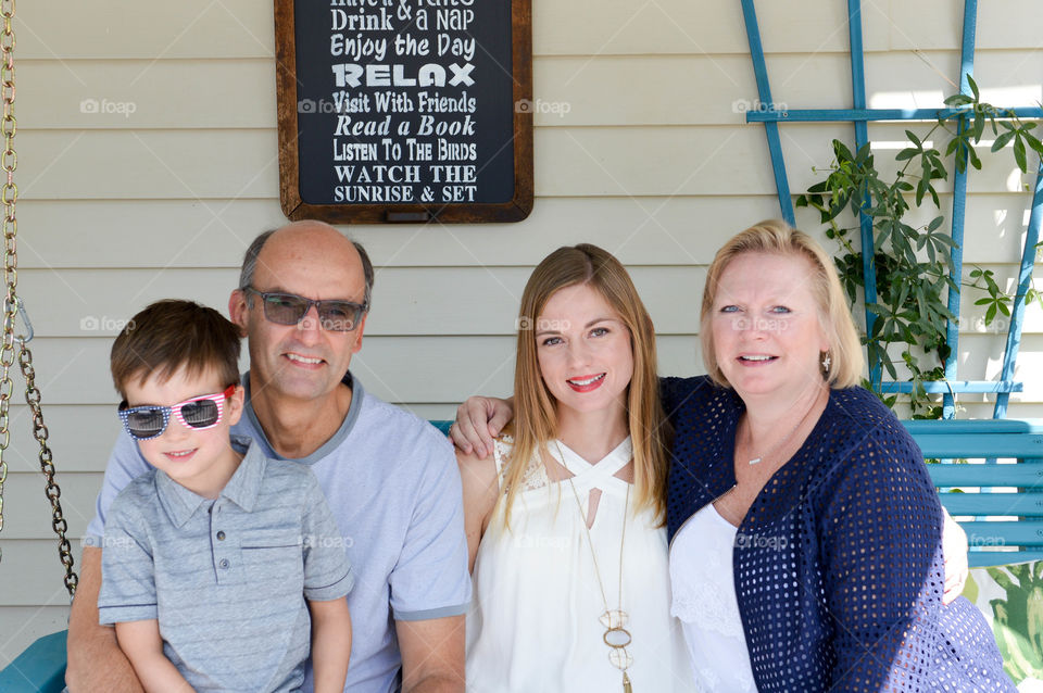 Family portrait on a porch bench swing outdoors on a bright summer day