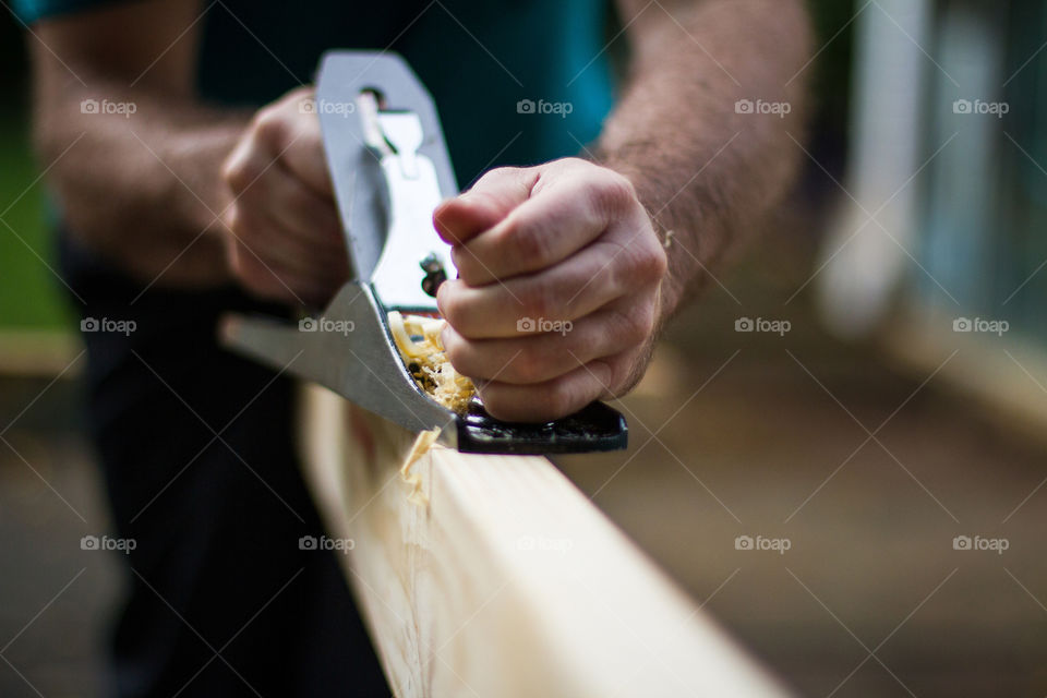 DIY at home preparing wood using a hand plane tool. Image of man working on wood.