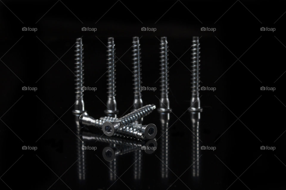 Set of silver color screws on black background