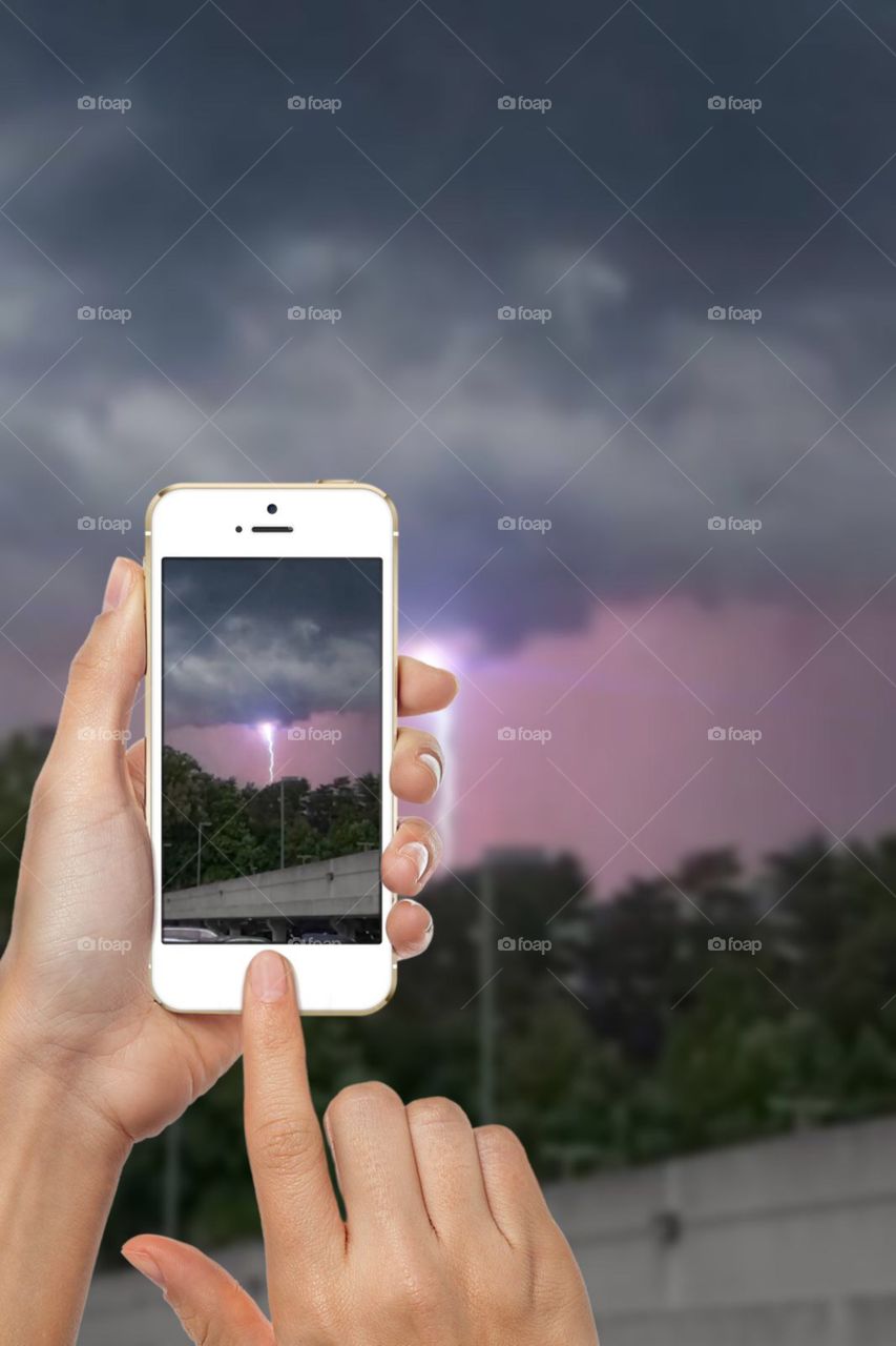 Using my mobile device to take a photograph of a lightning bold during a thunderstorm 