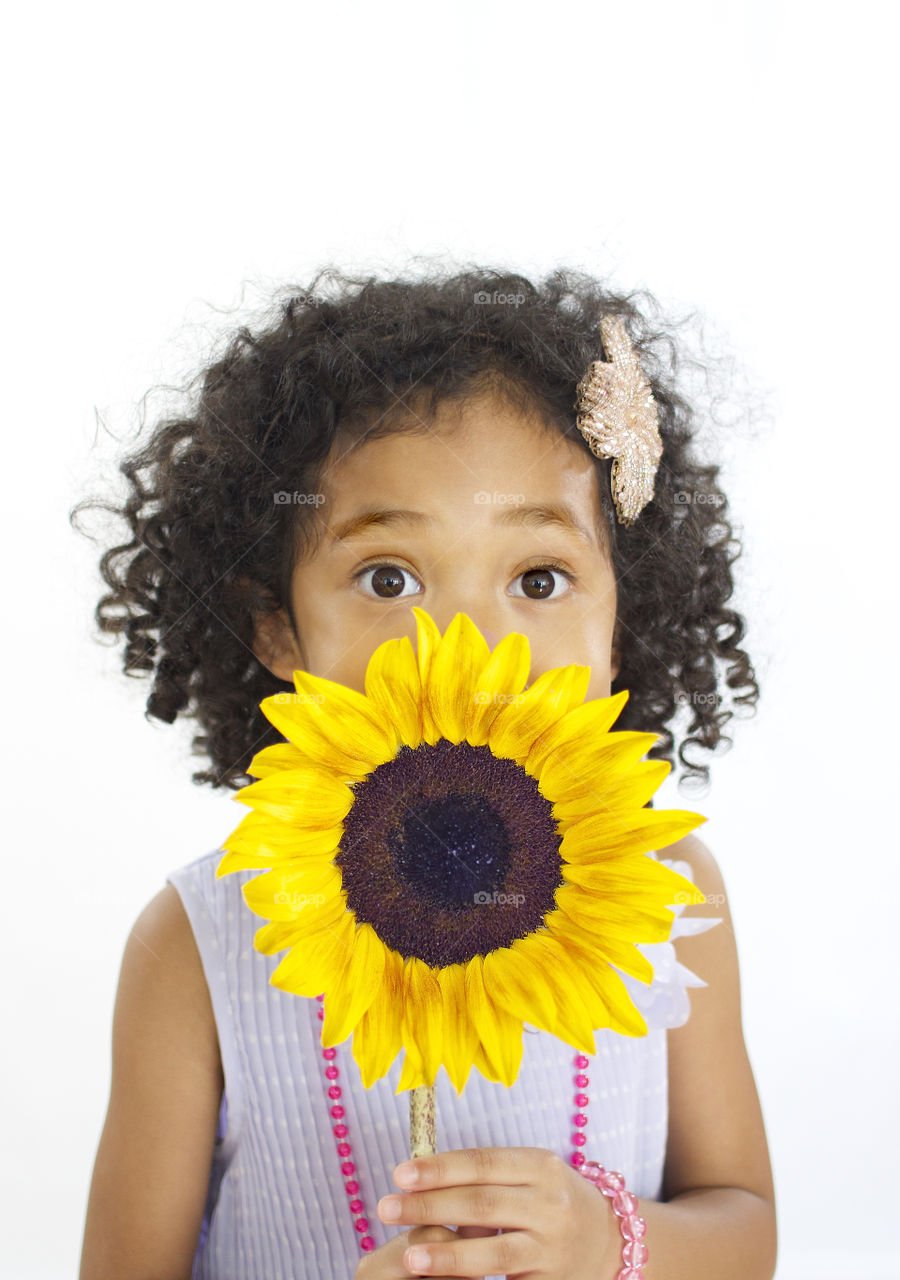Flower Girl. A girl hides behind a sun flower. 