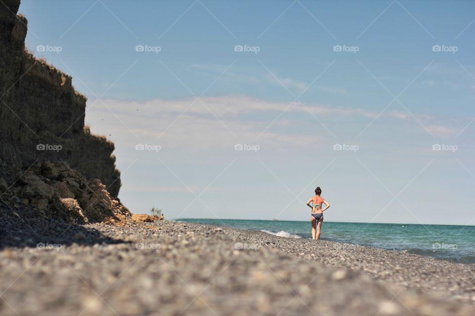 A girl stands on the shore and looks into the distance