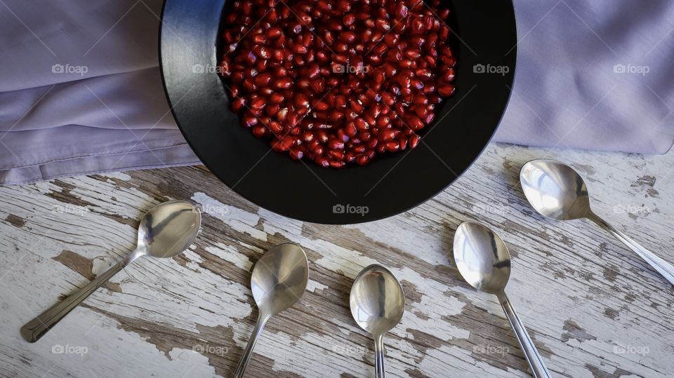 peeled pomegranate on a black plate and spoon