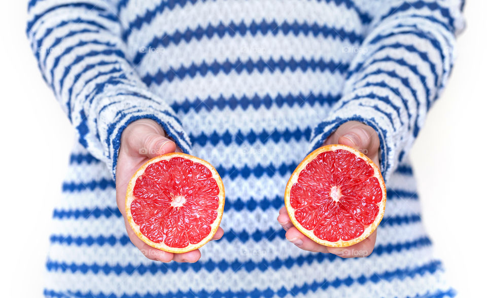 Juicy grapefruit cut in half in woman’s hands