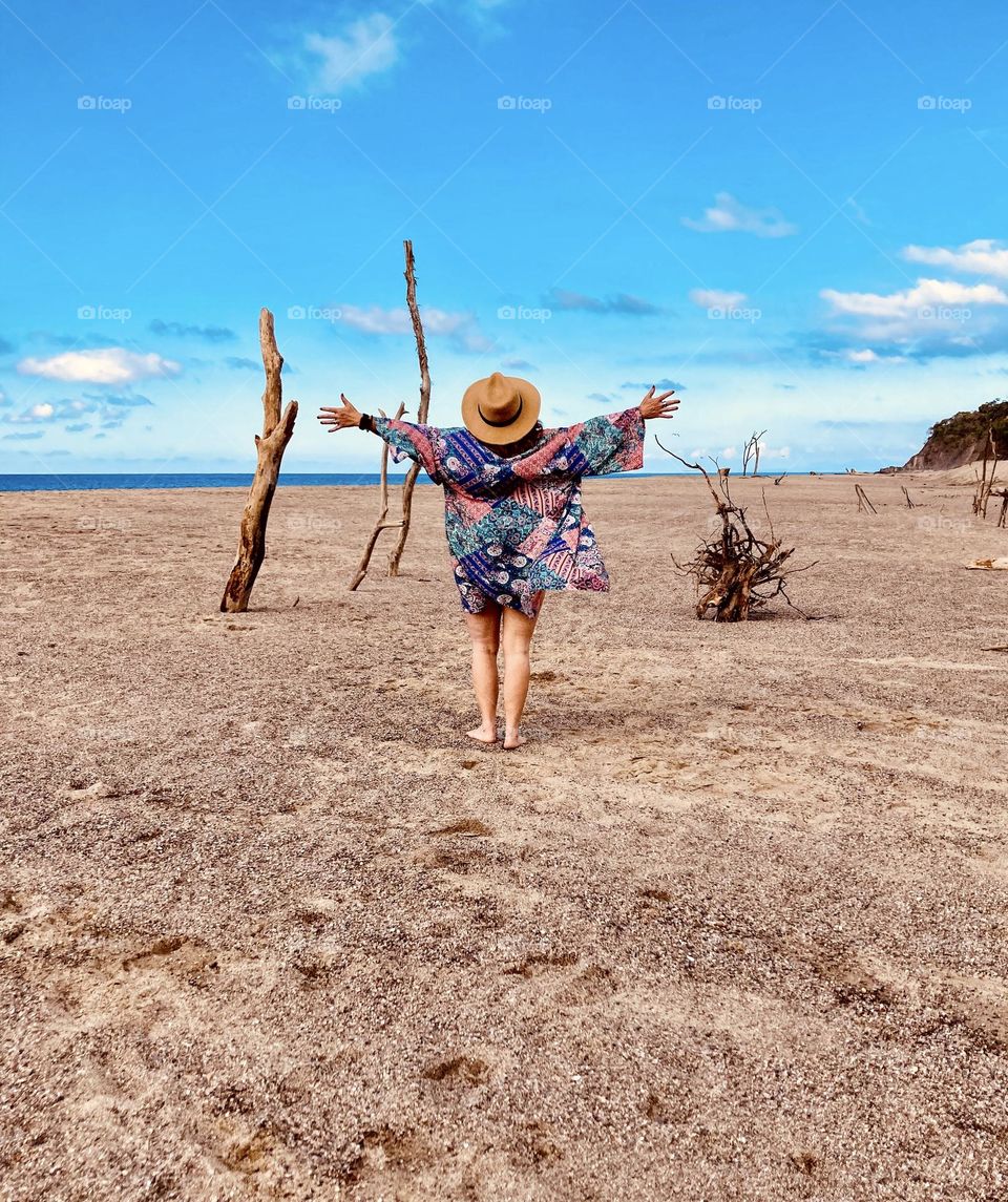 A woman with outstretched arms takes in the beauty of Lo De Marcos beach.