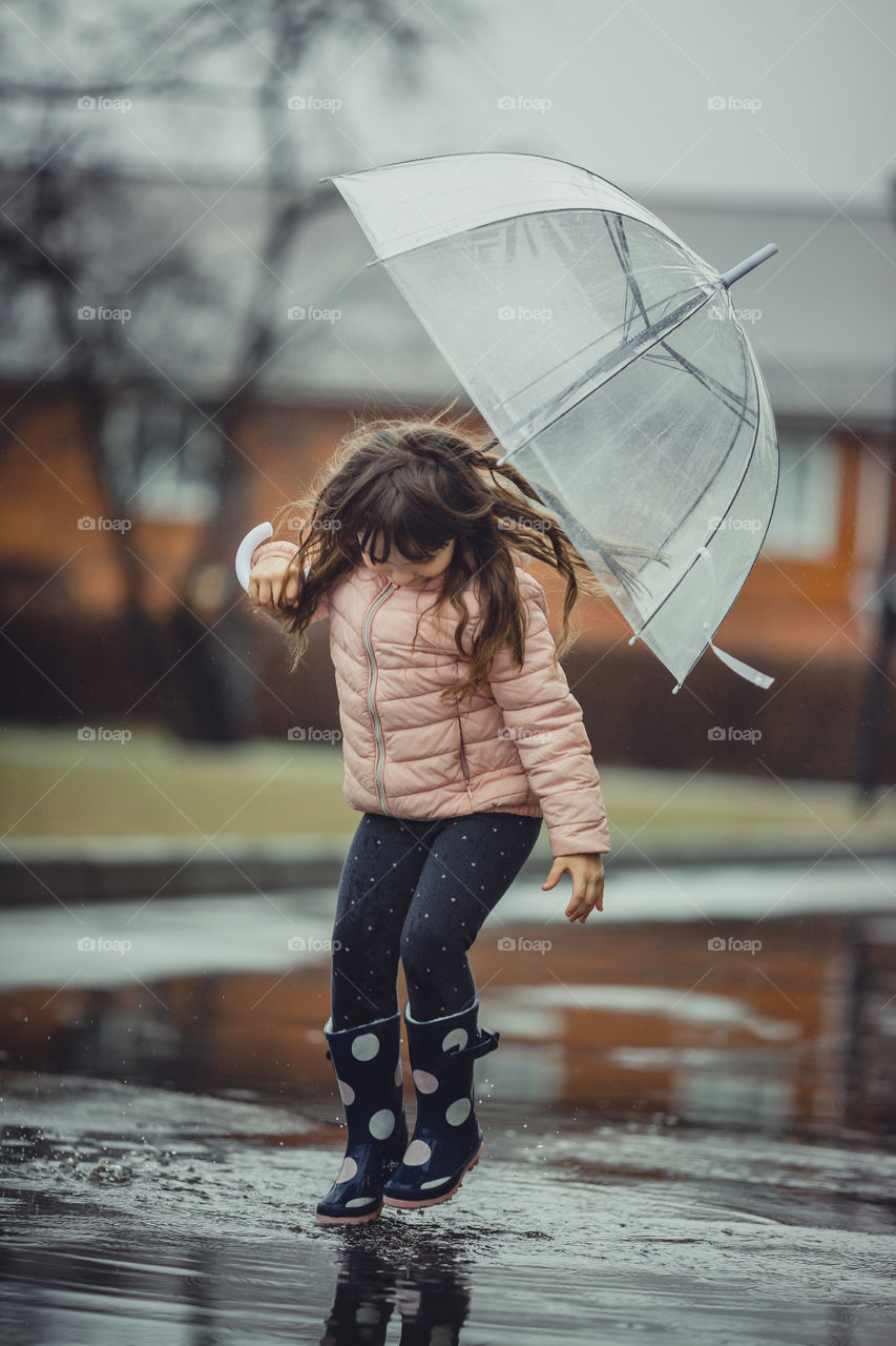 Little girl have fun under the rain.