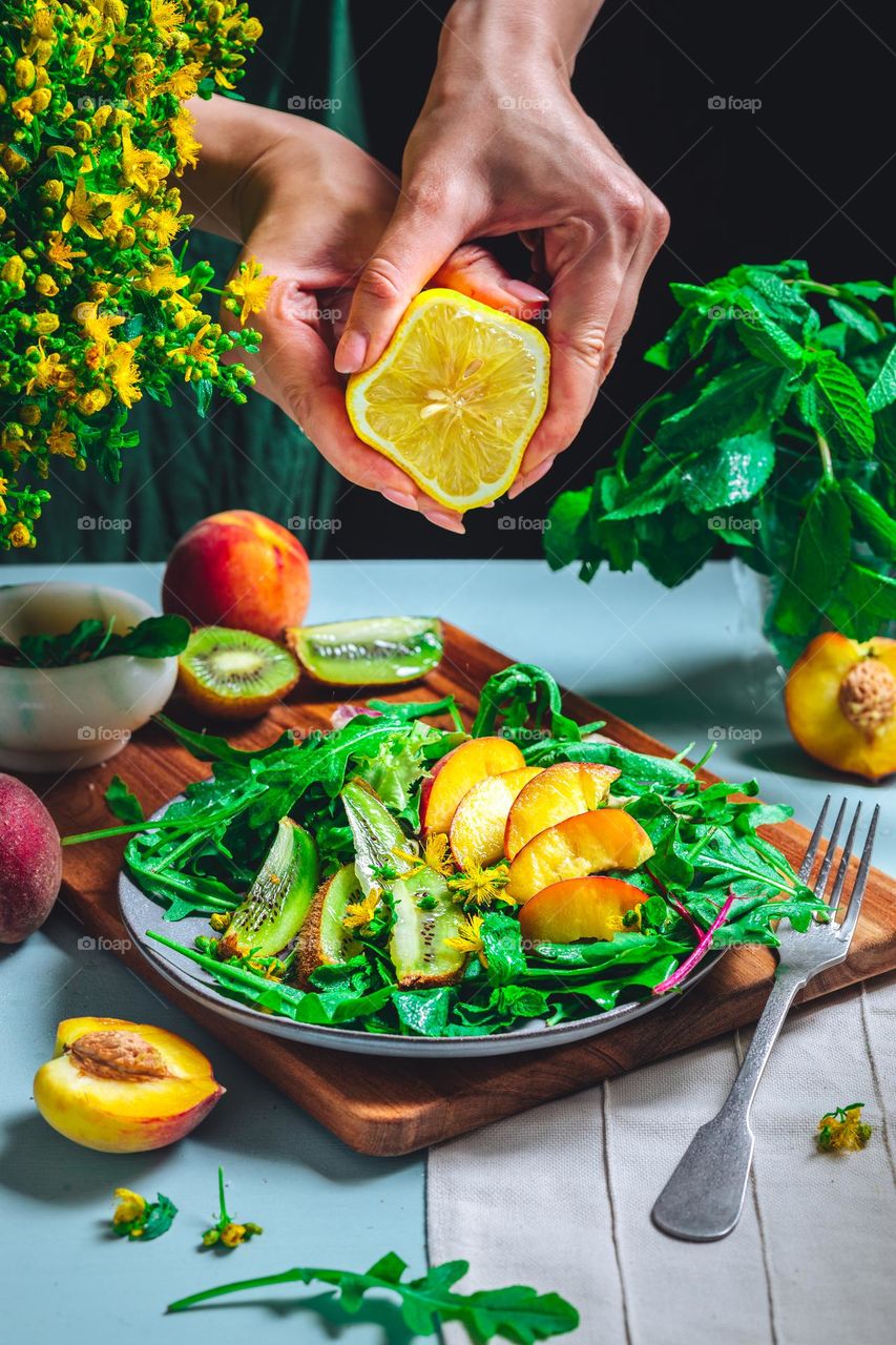 the girl prepares a bright summer salad of peaches, kiwi, arugula, and fragrant oil - vitamin mood, healthy lifestyle and delicious food. Diet and rational nutrition