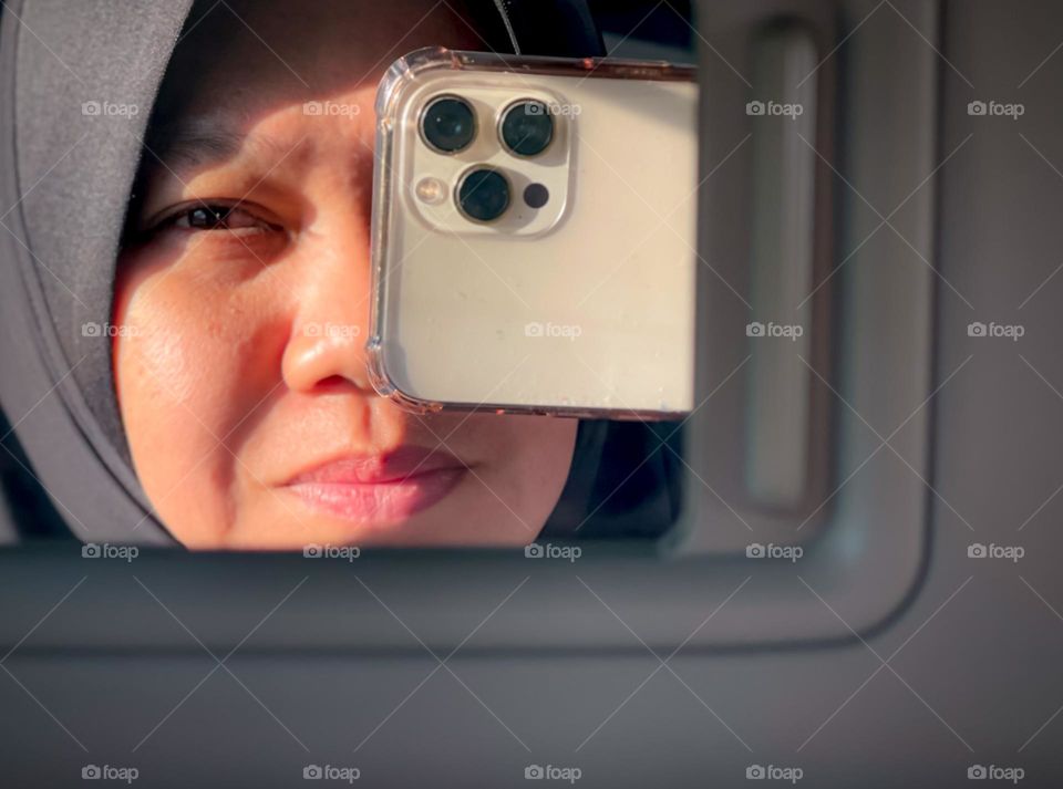 Selfie of a woman looking at the mirror in the car