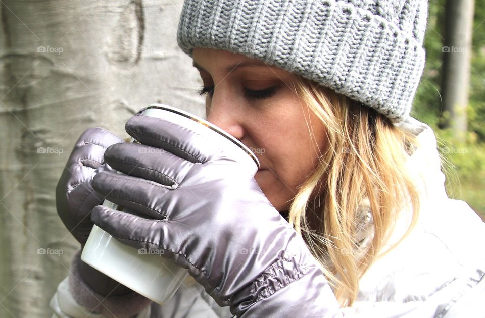 Woman enjoying hot coffee in winter with wood background. Hot coffee is a great winter drink that keeps you warm on inside and keeps your hands warm on the outside!