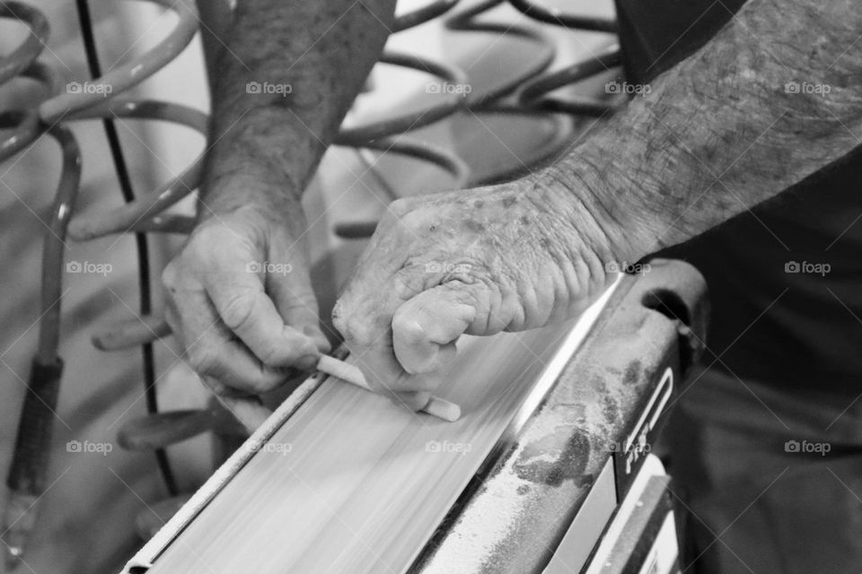 Old carpenter hands smooth a piece of wood