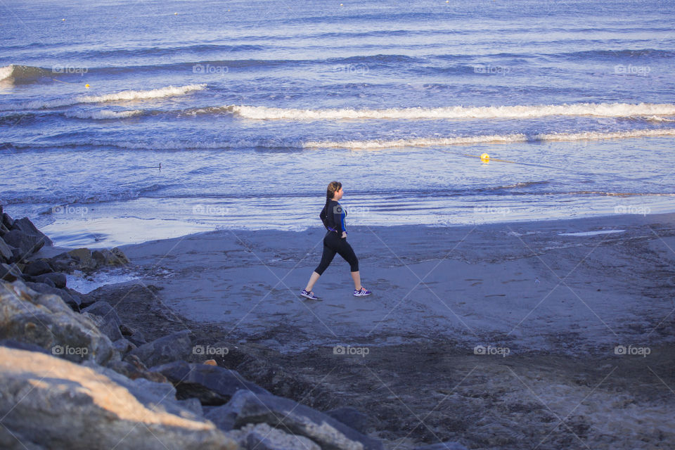 a young woman in the beach stretching for a run in the morning