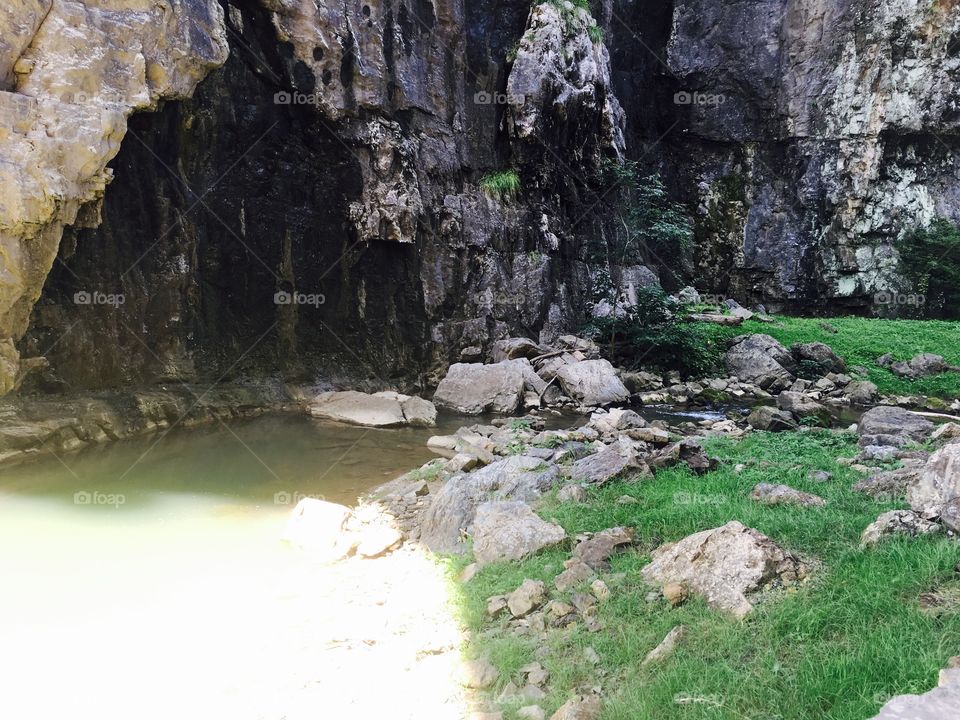 Just outside this cave lies a serene field on the bank of a gentle stream