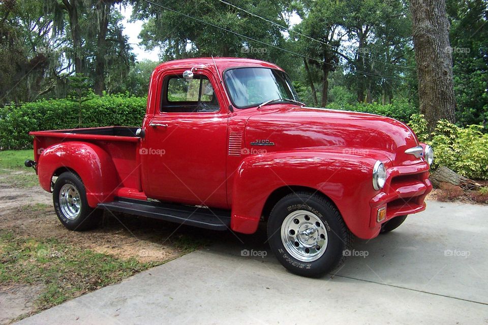 Bright red antique Chevy Truck in a rural log and trees greenery background a love for days gone by