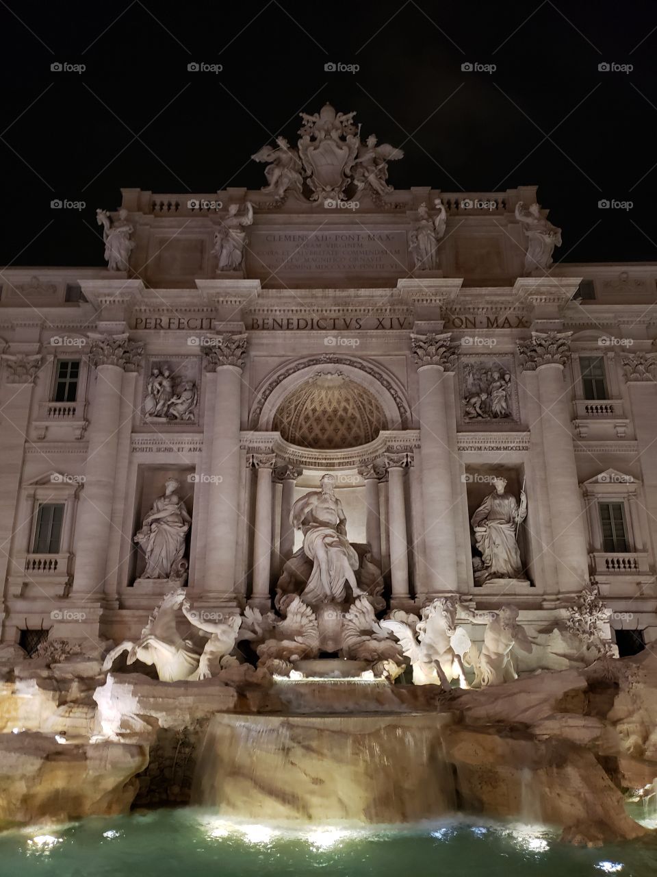 The famous Trevi fountain in Rome, Italy, Europe, in evening time with lights illuminating the statues and water.