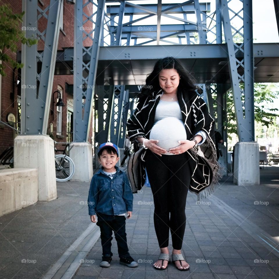 Expecting mother with her 3 year old smiling and waiting to be a big brother