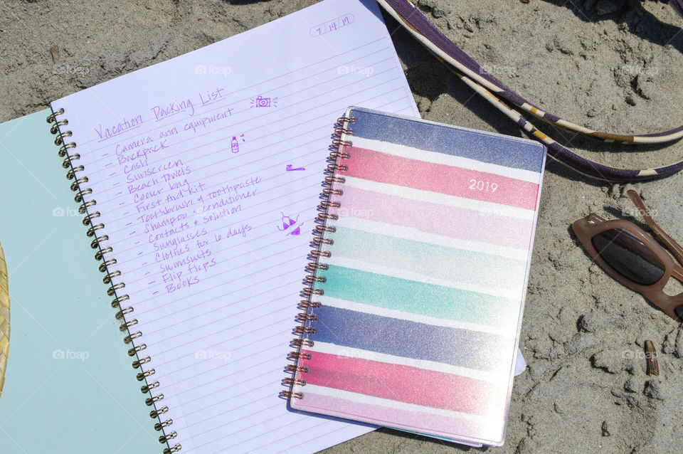 Notebook and planner laid out on the beach