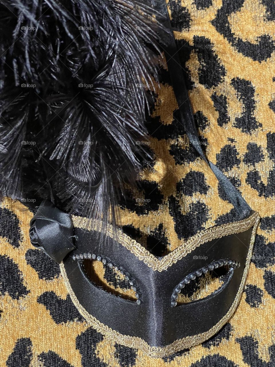 satin mask and black feathers on an animal patterned background, carnival season, costumes and masks