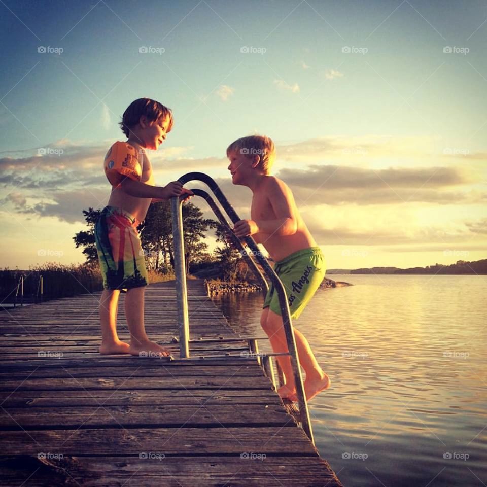 Two brothers at pier, bathing in the sunset