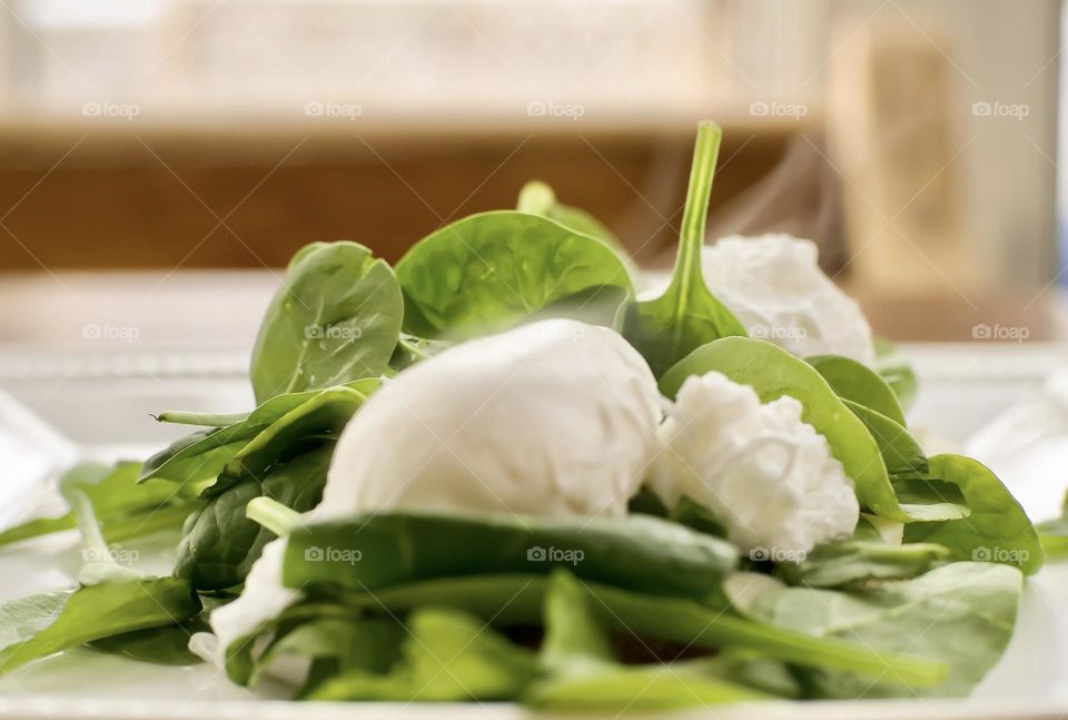 Steaming poached eggs on a bed of spinach.