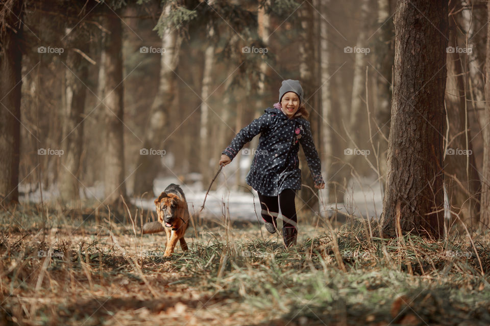 Girl walking with German shepherd puppy in a spring forest 