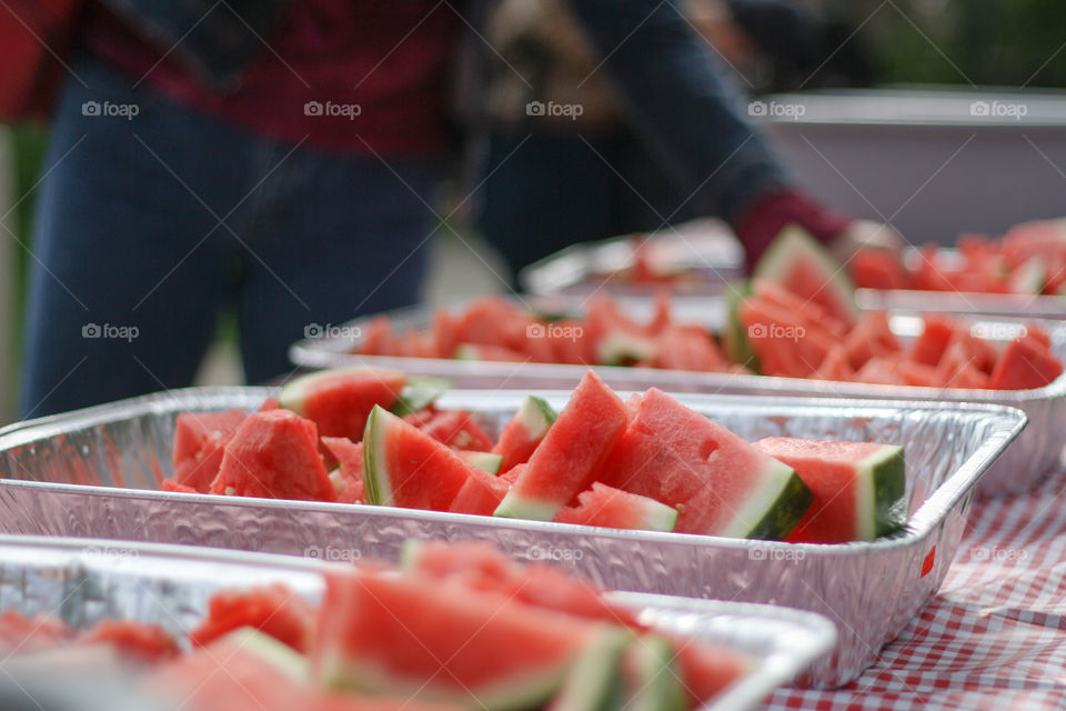 A person selects a fresh piece of watermelon at a picnic BBQ
