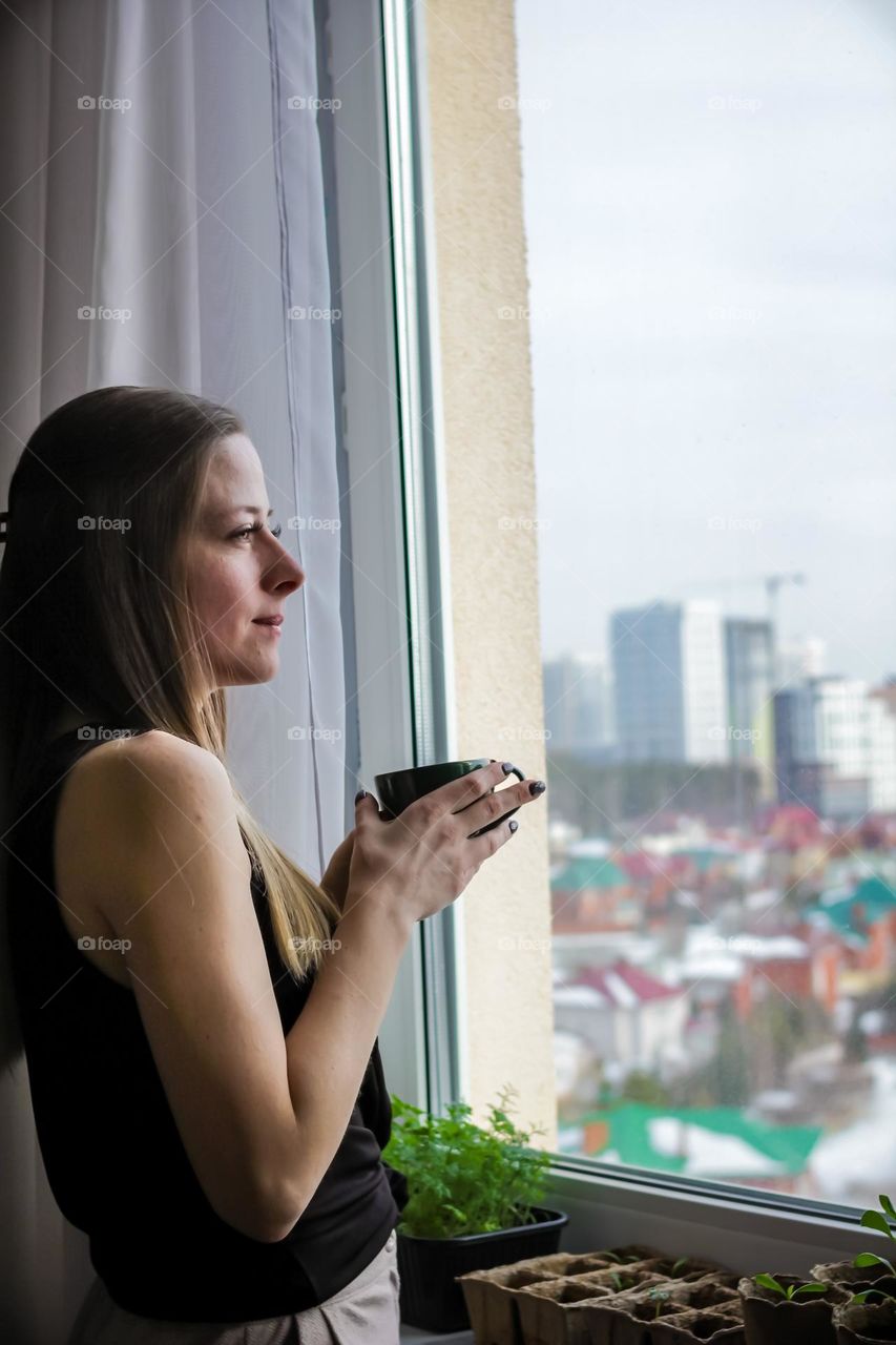 Beautiful woman  drinking coffee near window 