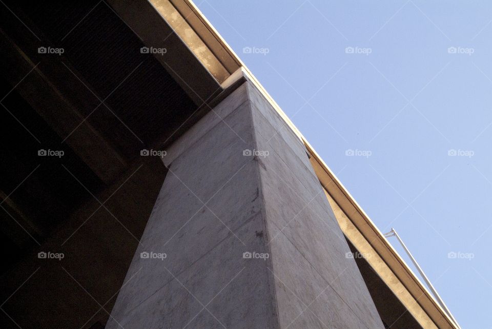 Looking straight up at a massive column that helps support a bridge.