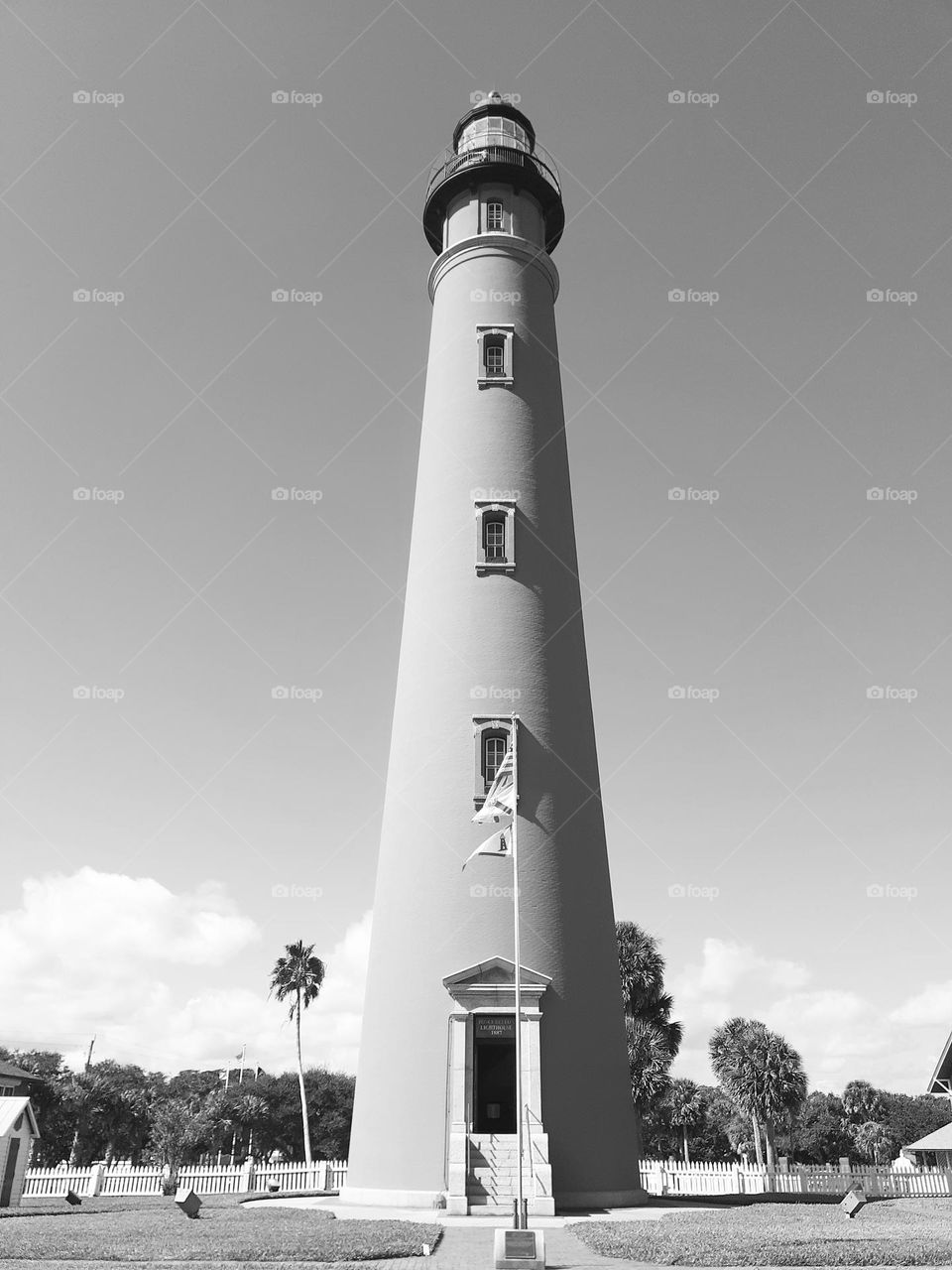 A black and white photo of the tall Ponce Inlet Lighthouse stretching up to the sky.