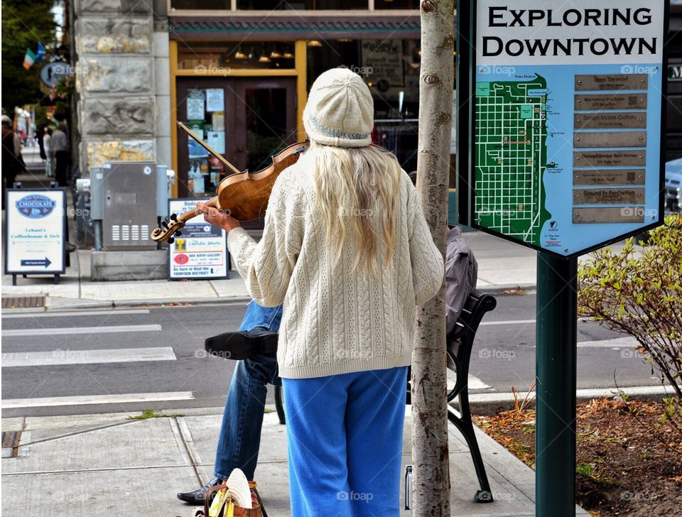 Elderly woman playing violin on street corner