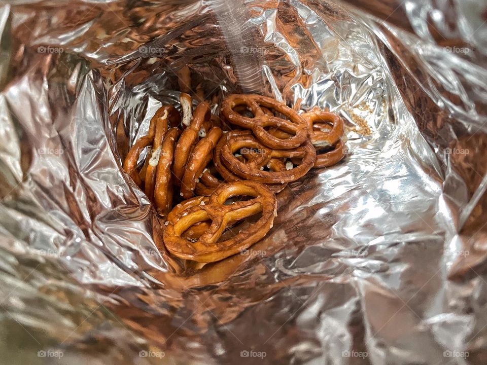 Look into a silver colored bag on small brown pretzels