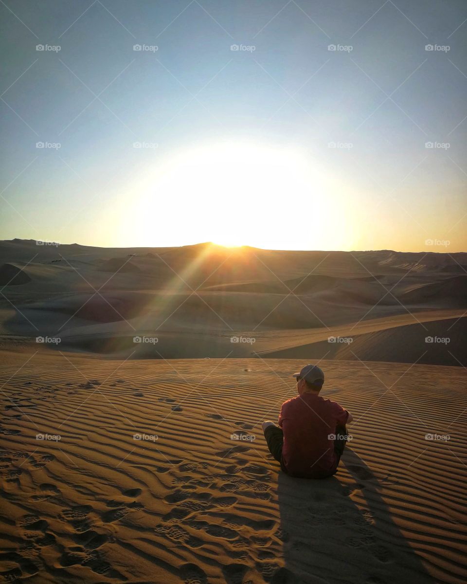 Watching the sun set over the desert sand.