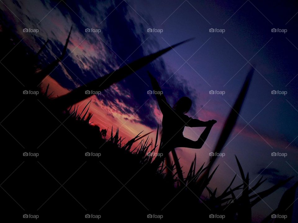 Girl in acrobatic pose on sunset background