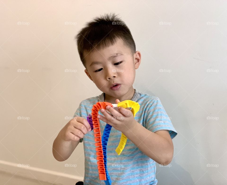 Asian boy playing with colourful toys 