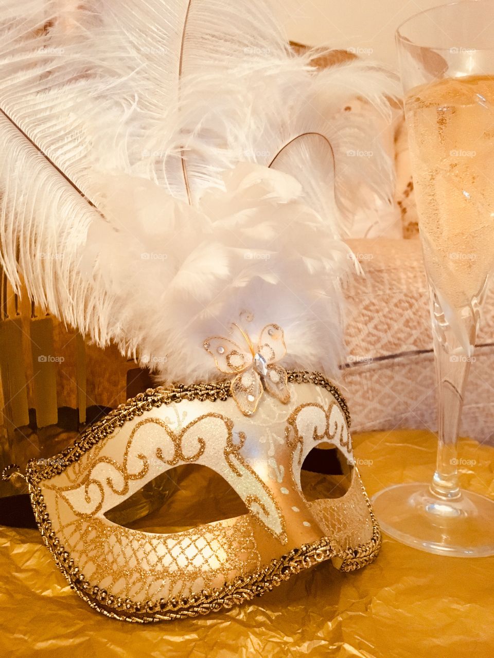 Close up view of gold Venetian masquerade mask with a bottle of Moscato and a glass of white grape juice 