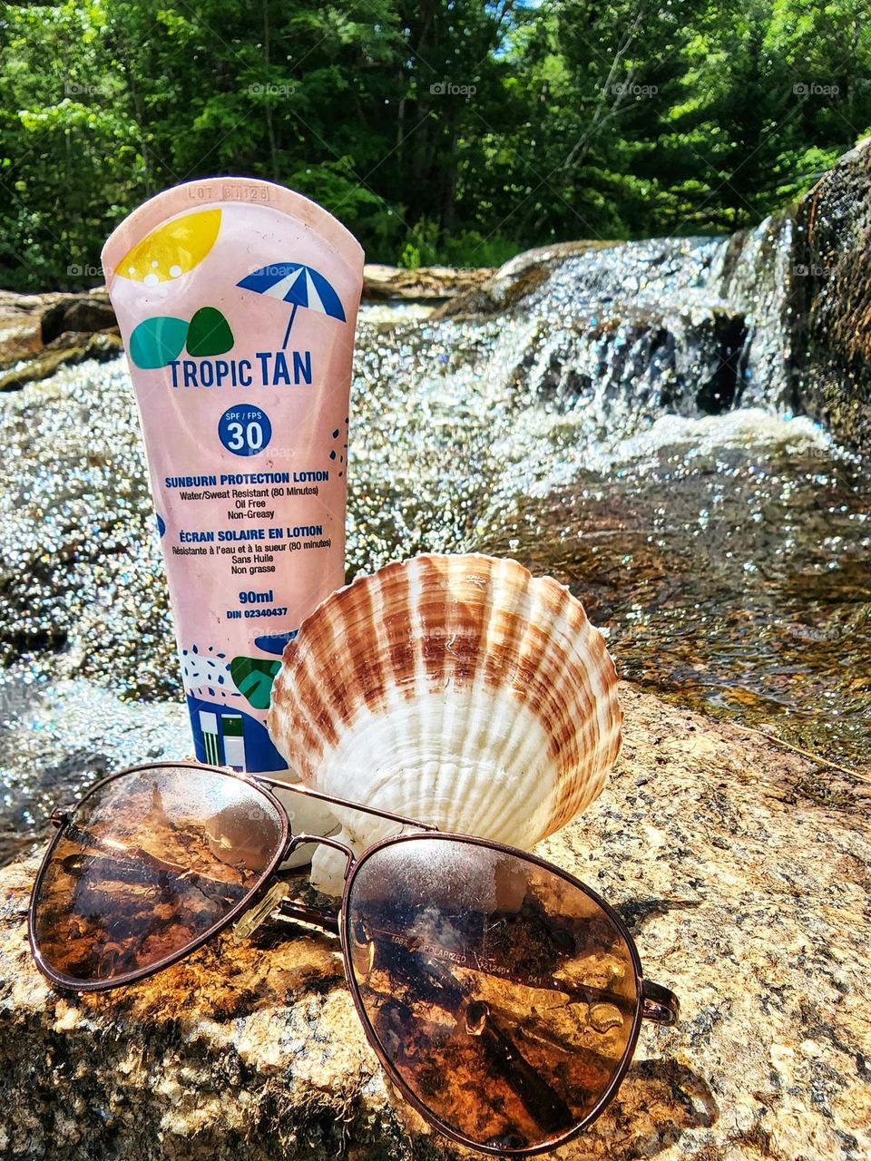 TropicTan sunscreen on a rock surrounded by cascading water.