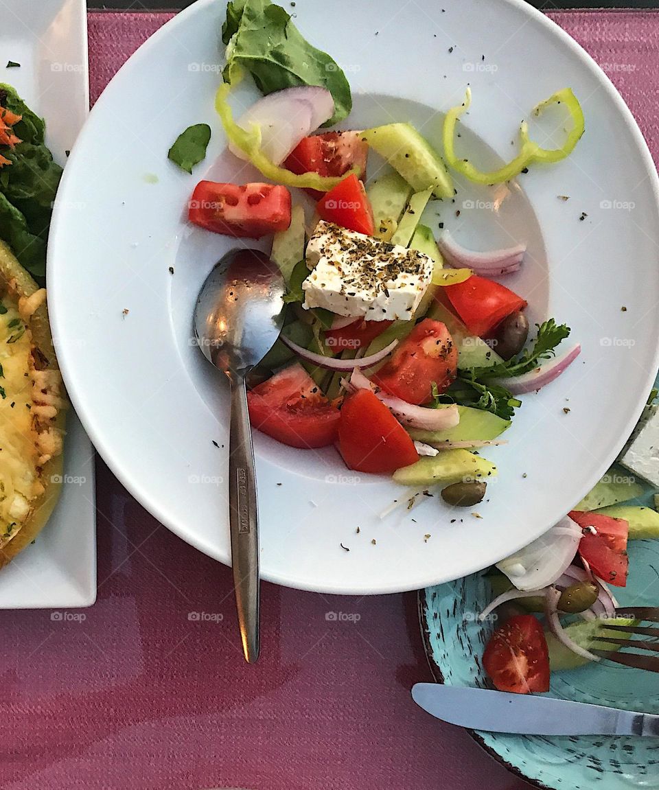 Greek salad with fresh vegetables on a white plate at a restaurant 