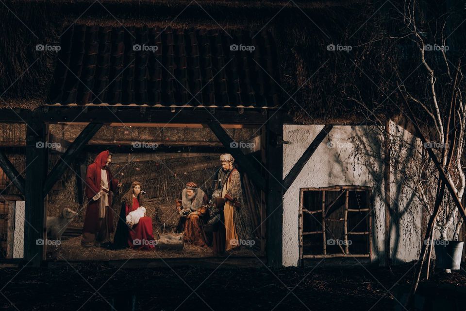 Beautiful view of the installation of the barn with mannequins of the Virgin Mary, the Magi and the baby Jesus Christ in the manger in the night city of Brussels on the Grand Place in Belgium, side view close-up.