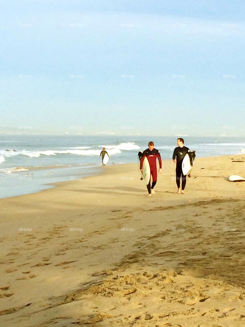 Heading to the office. Surfers walking the shoreline.