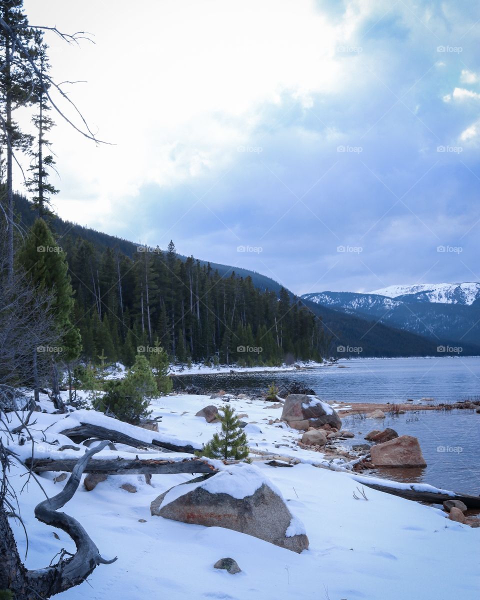Walk down the rocky snow covered shoreline on a cold windy day.