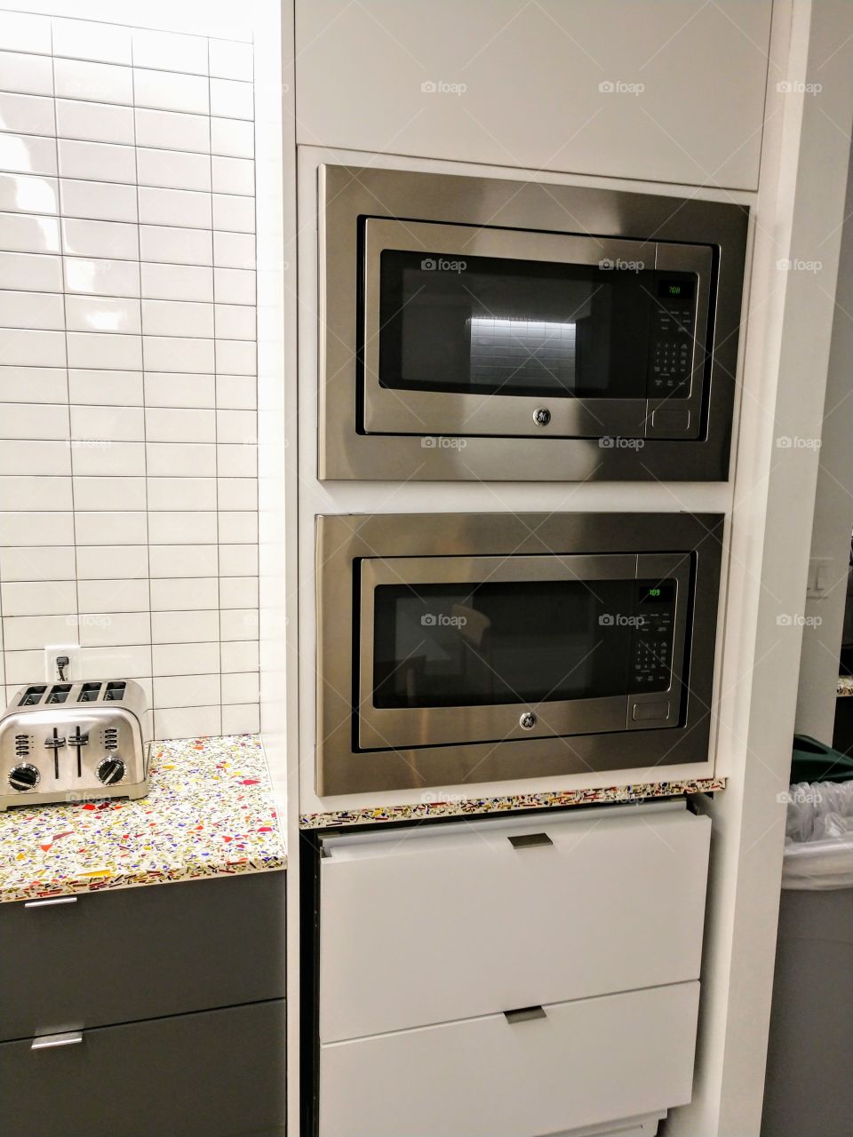 Two level microwave ovens next to toaster on counter