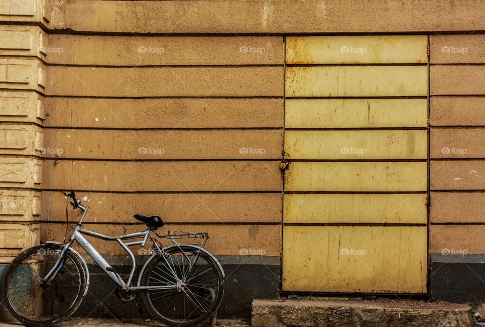 old vintage bicycle parked against old yellow wooden wall with lines...