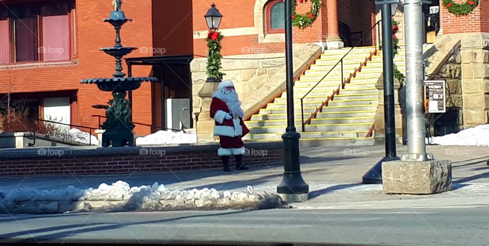 Santa standing on a street corner downtown in front of City hall