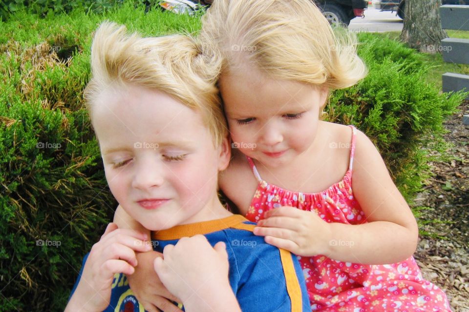 Gorgeous photo of two young children hugging each other during a windy afternoon! 