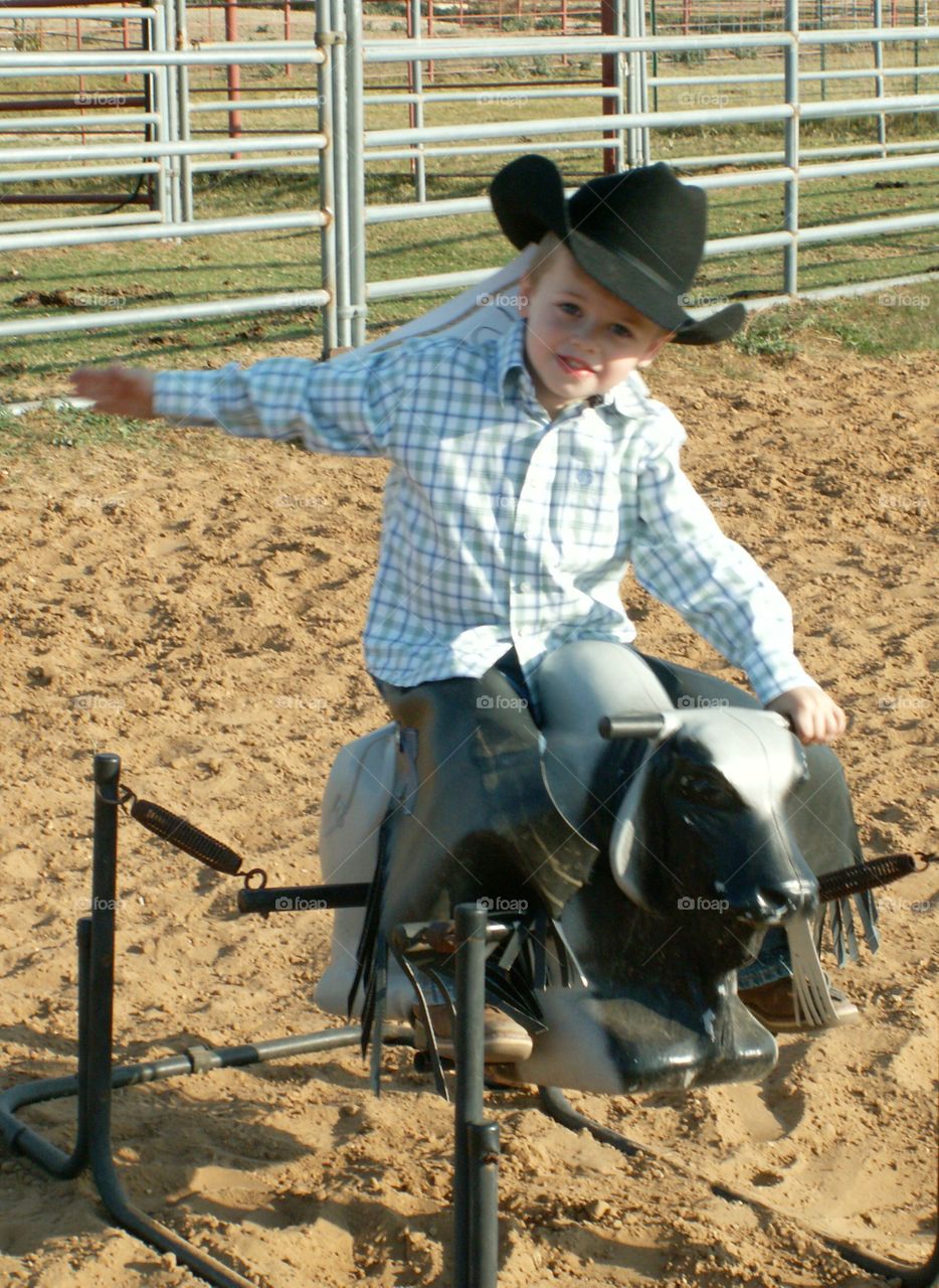 Small kid sitting on rodeo bull